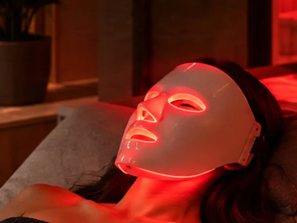 Client relaxing with a red LED face mask at Fast & Fit